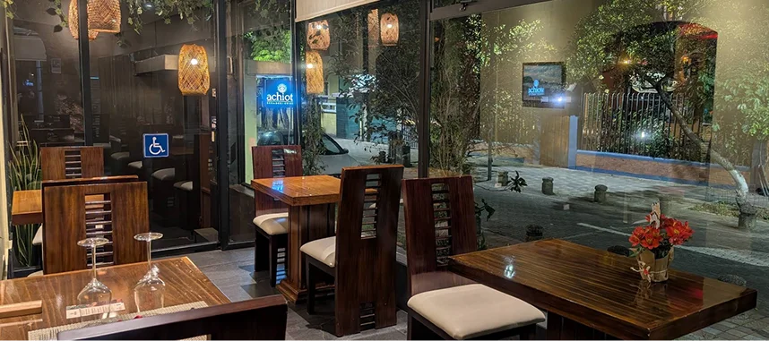 Restaurante Achiote en Quito: interior moderno con mesas de madera y vista exterior.