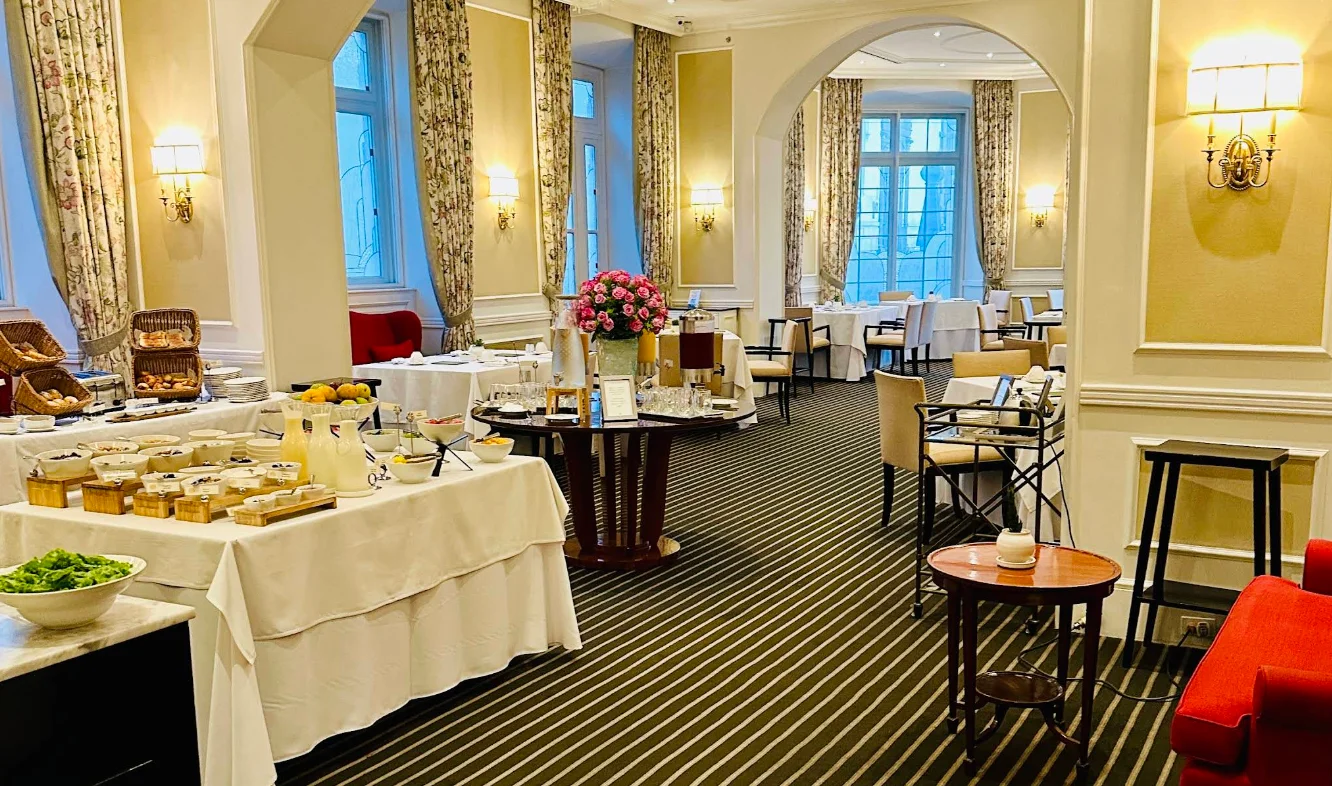 Buffet de desayuno en el elegante salón de Casa Gangotena con decoración clásica y ventanales amplios.